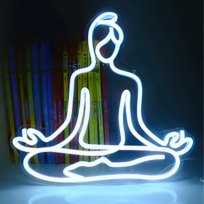 A neon sign depicting a woman practicing yoga in white LED lights