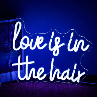 Love is in the hair neon sign for a hair salon in blue LED lights