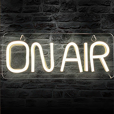 On air LED sign in white lights on black brick wall