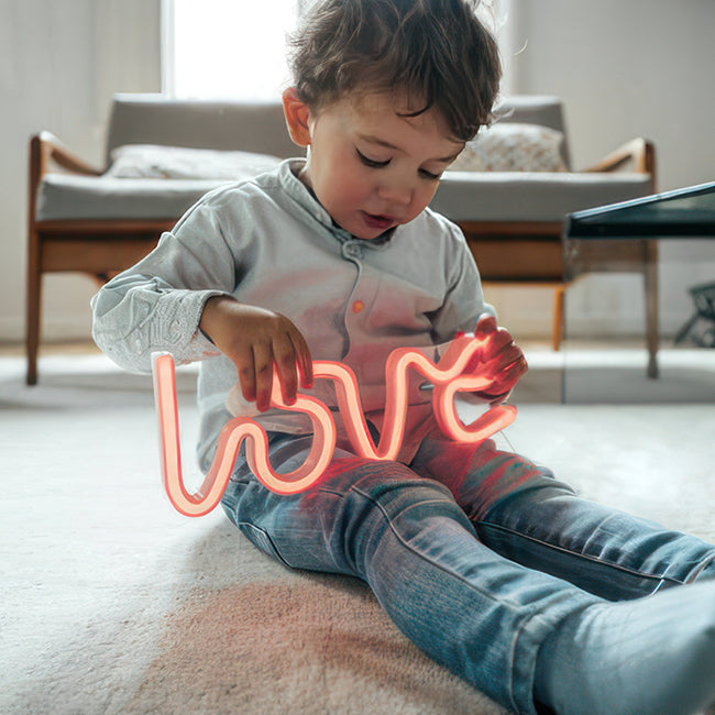 Little boy with love LED neon sign in his lap